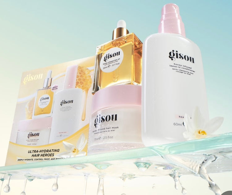 Gisou hair product Diwali gift set featuring oil, conditioner, hair mask, and hair fragrance on a glass shelf with water drips.