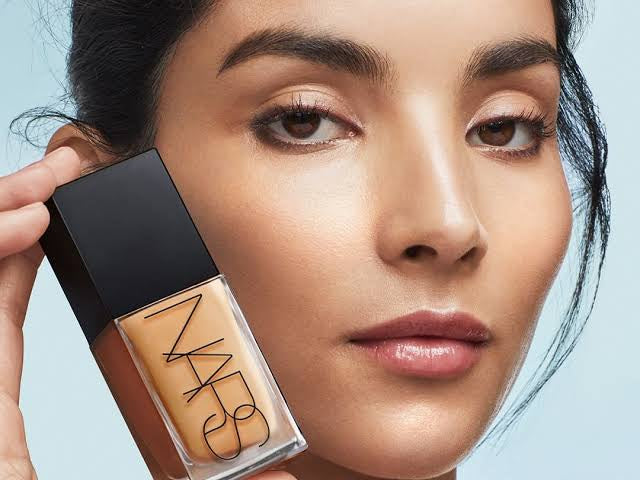 A close-up of a hand holding a nars beauty product.