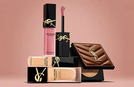YSL Beauty makeup products arranged in a stack against a pale pink background, including foundation, blush, and bronzer.