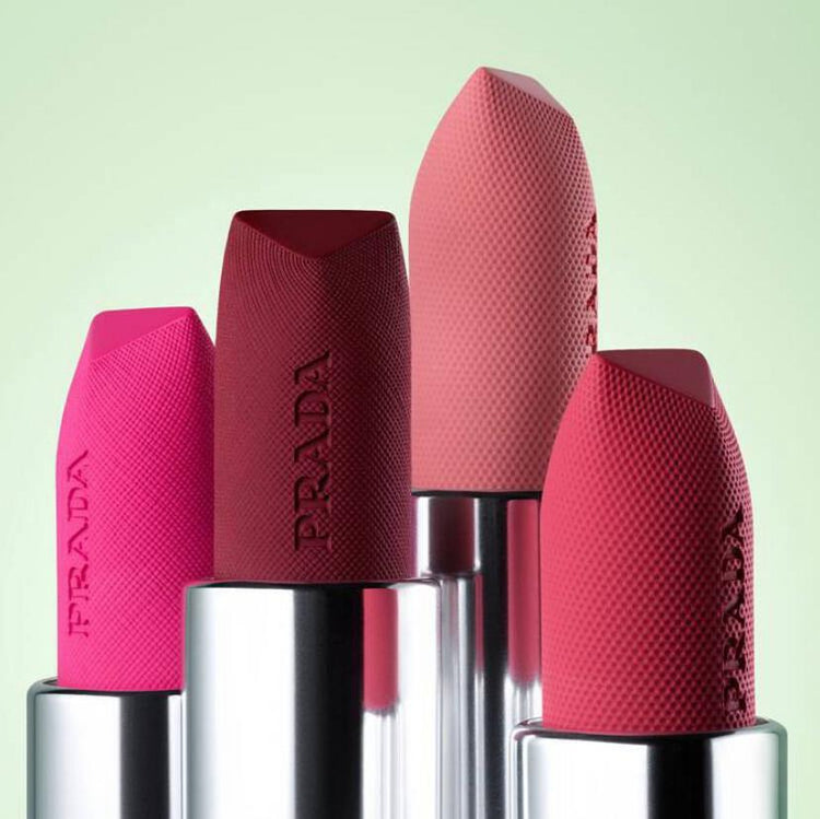 Four bold Prada lipsticks in varying shades of pink and red, featuring unique, textured caps.