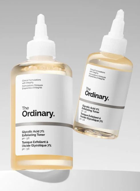 Two bottles of The Ordinary Glycolic Acid 7% Exfoliating Toner are displayed on a neutral background. Each bottle contains a clear, light yellow liquid, and the label is white with black text.