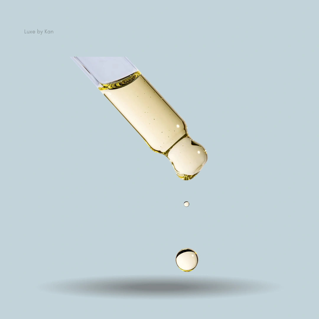 Augustinus Bader Hair Oil dropper releasing golden oil droplets.