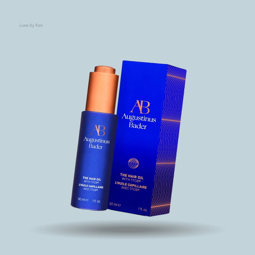 Augustinus Bader Hair Oil with its signature blue and copper bottle, displayed alongside the matching box.
