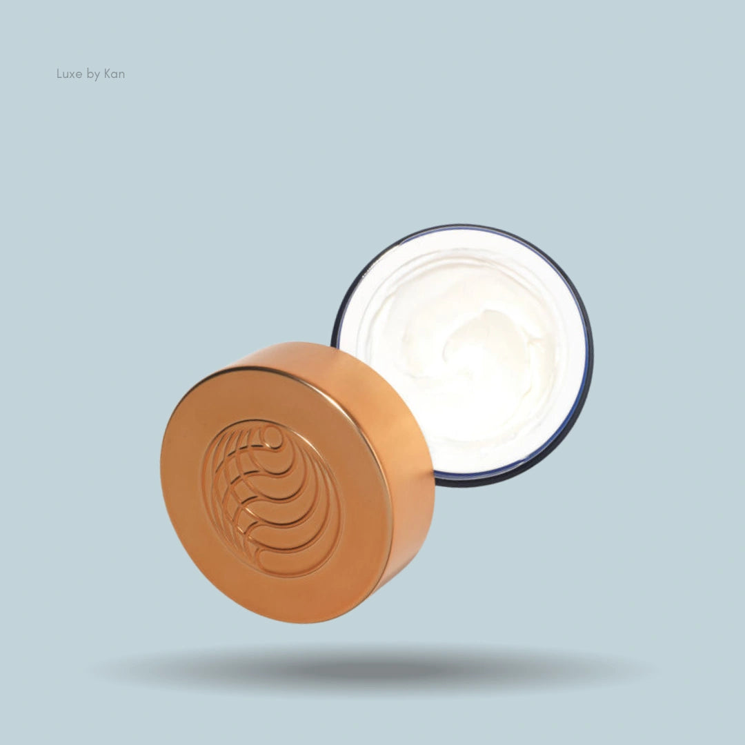 Open jar of Augustinus Bader The Ultimate Soothing Cream, gold lid with circular swirl design.