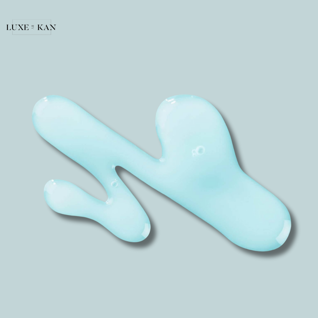 Light blue gel-like substance smeared on a soft gray background, showcasing a smooth and glossy texture.