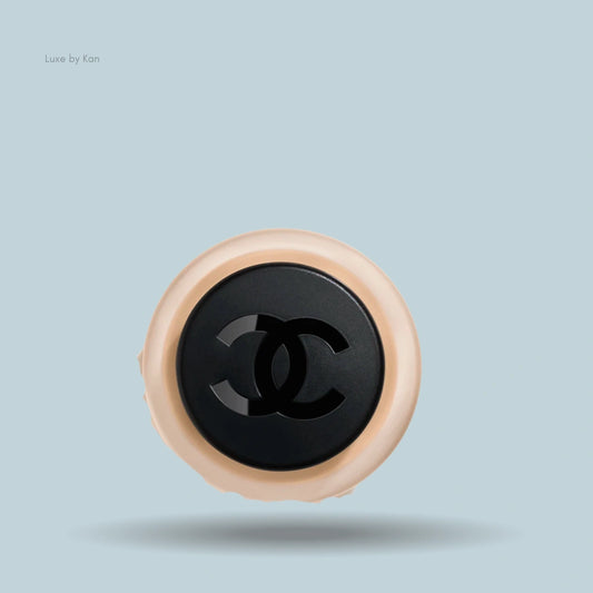Chanel n°1 de Chanel revitalizing foundation compact featuring the interlaced CC logo on a black lid with a peach-colored base.