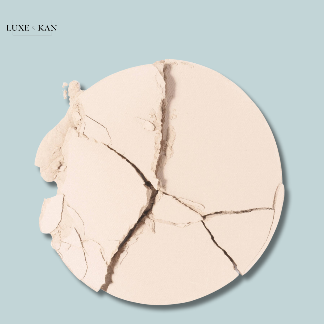 Close-up of cracked Chantecaille HD Perfecting Powder on a pale blue background.