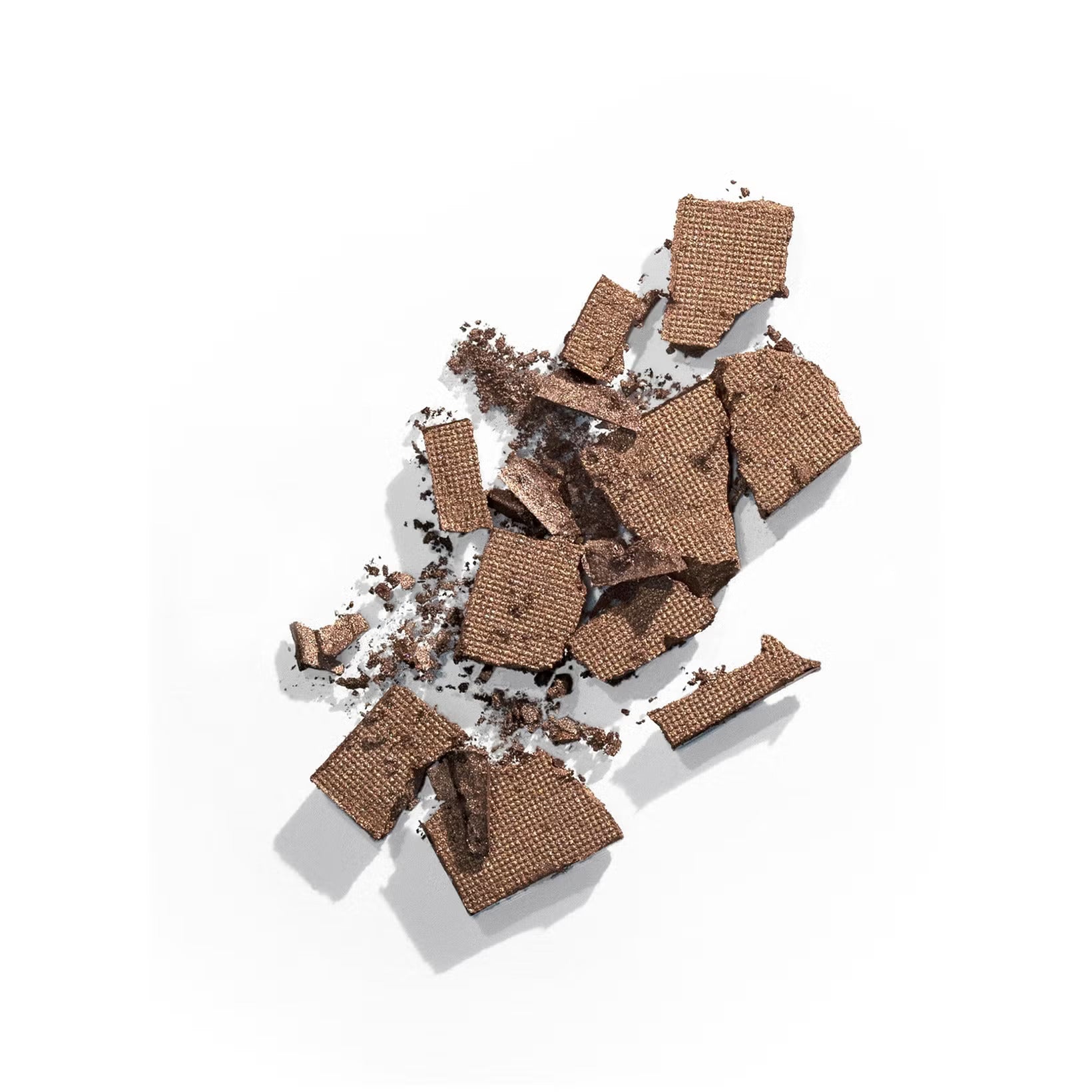 Crushed chocolate wafer pieces scattered on a white surface, showcasing their texture and fine crumbs.
