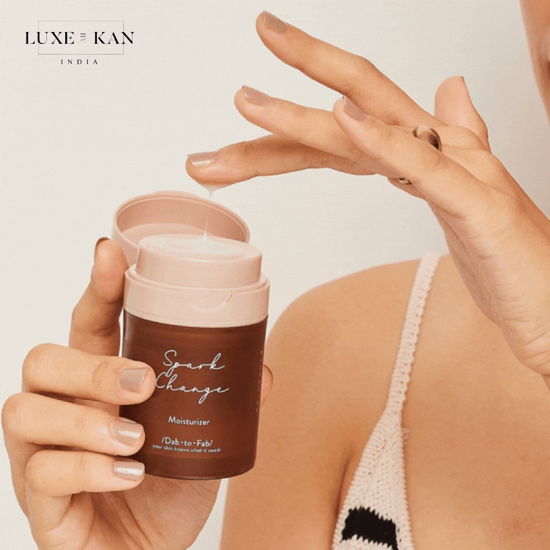 A person holds a brown DAB TO FAB moisturizer jar labeled "Spark Change" with a pink lid.