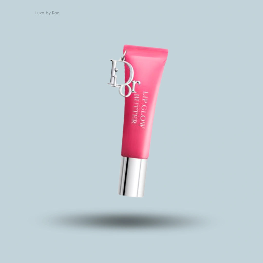 Pink Dior Lip Glow Butter tube, featuring a silver cap and Dior charm, elevated above a shadowed, light blue surface.