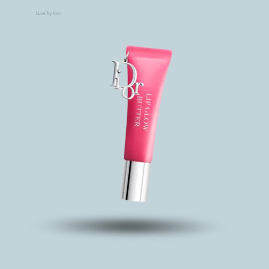 Pink Dior Lip Glow Butter tube, featuring a silver cap and Dior charm, elevated above a shadowed, light blue surface.