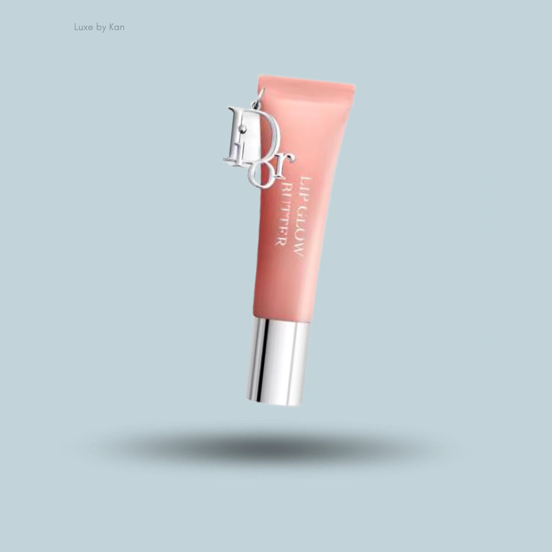 Dior Addict Lip Glow Butter in a soft pink tube with silver accents and a Dior logo charm.