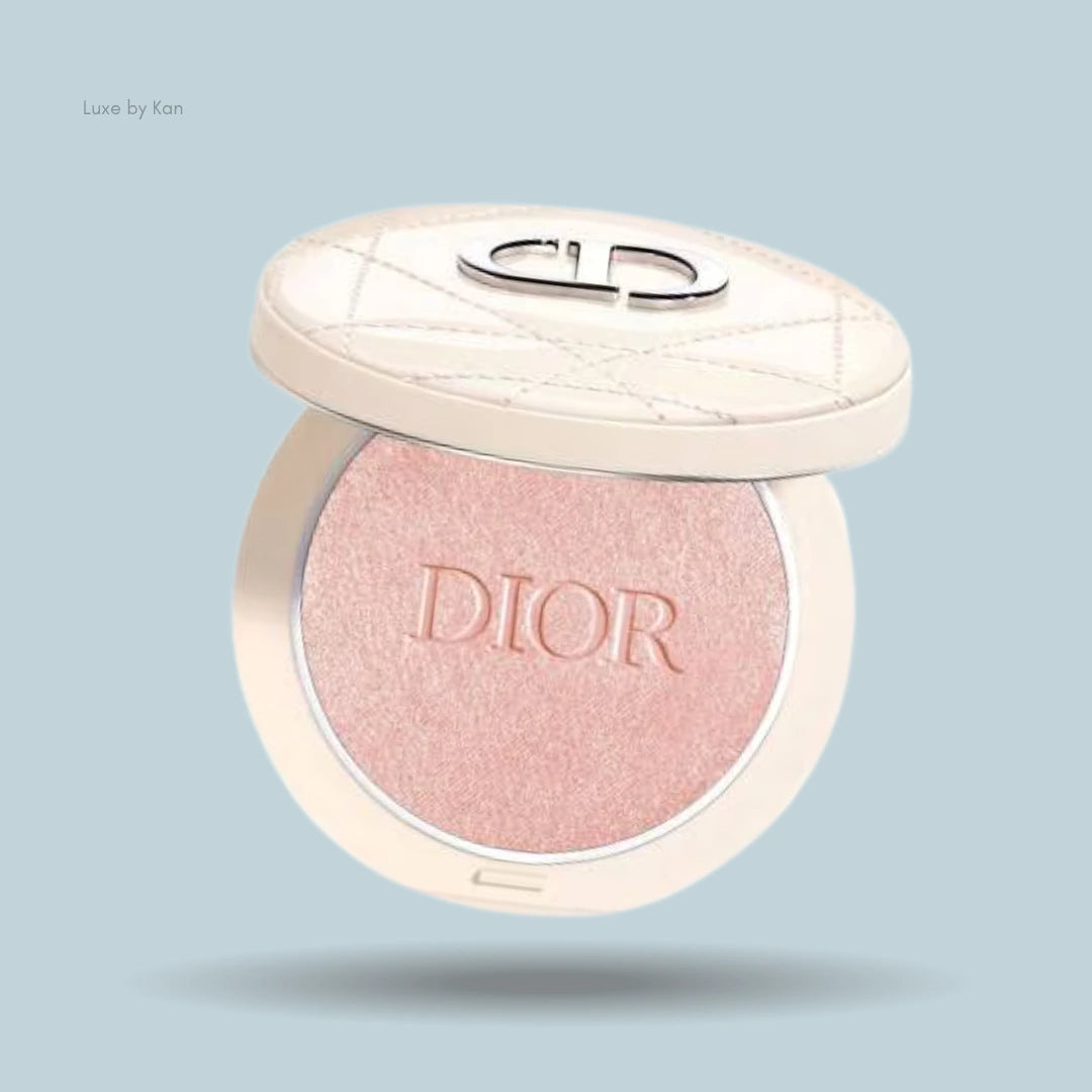 Close-up of an open Dior Forever Couture Luminizer compact. The powder inside is a pale pink shade with "DIOR" embossed on the surface.