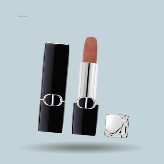 Dior Rouge New Velvet Lipstick in sleek black and silver packaging, featuring an exposed warm brown shade with a soft matte finish.