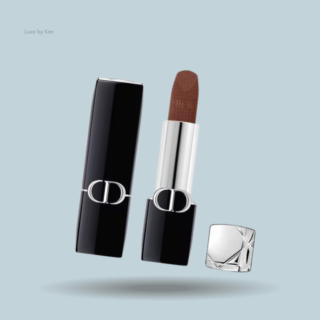 Dior Rouge lipstick in velvet finish, with black case and silver detailing, casting a shadow on a light blue background.