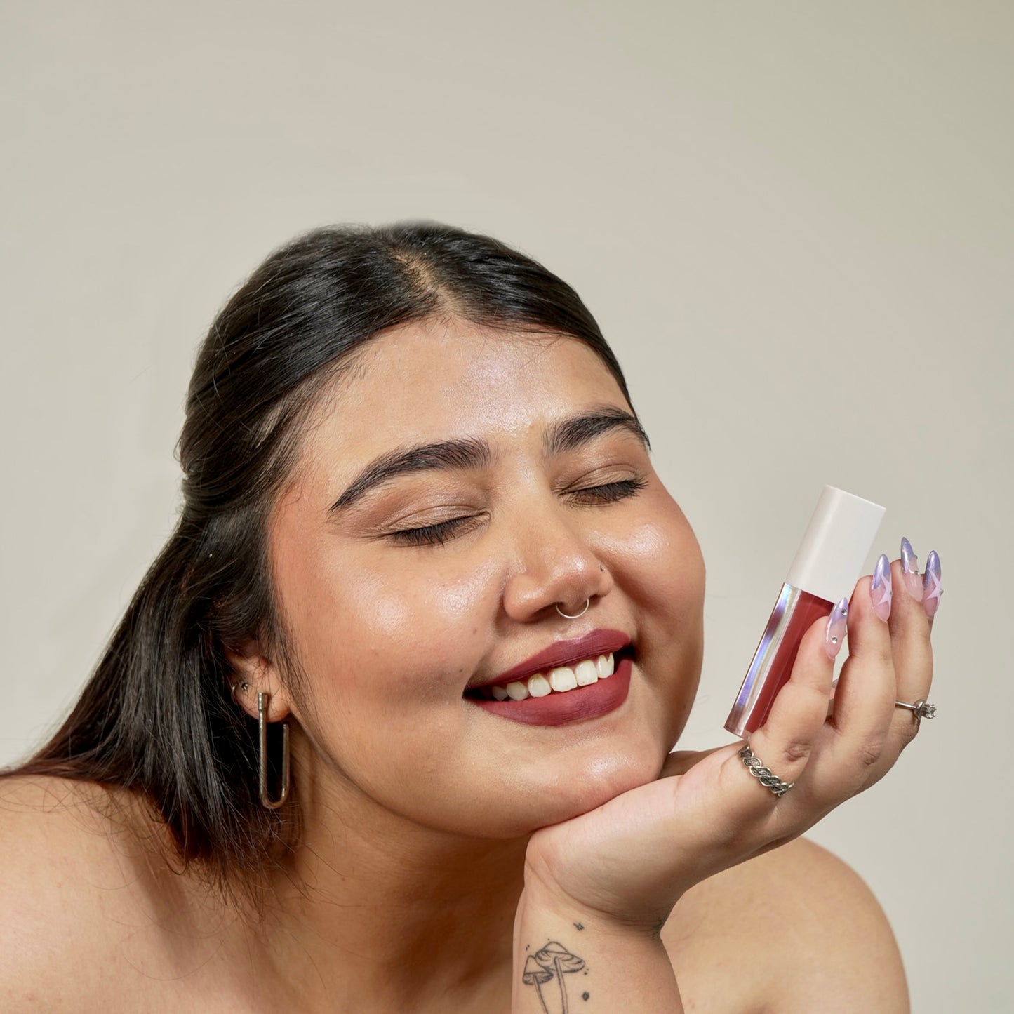 A close-up of a hand holding a era beauty rom-com lipstick shade product.