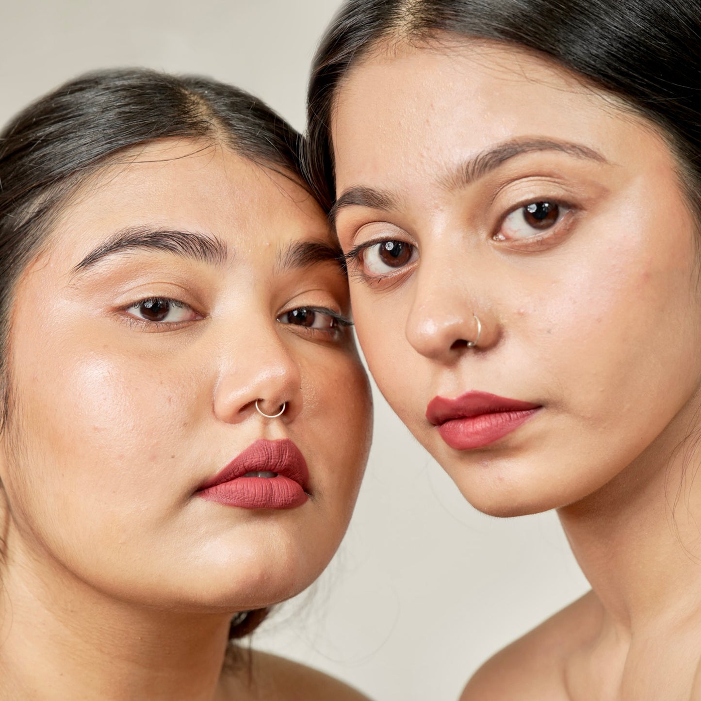 Two women face close-up with era beauty lipstick rom-com shade.