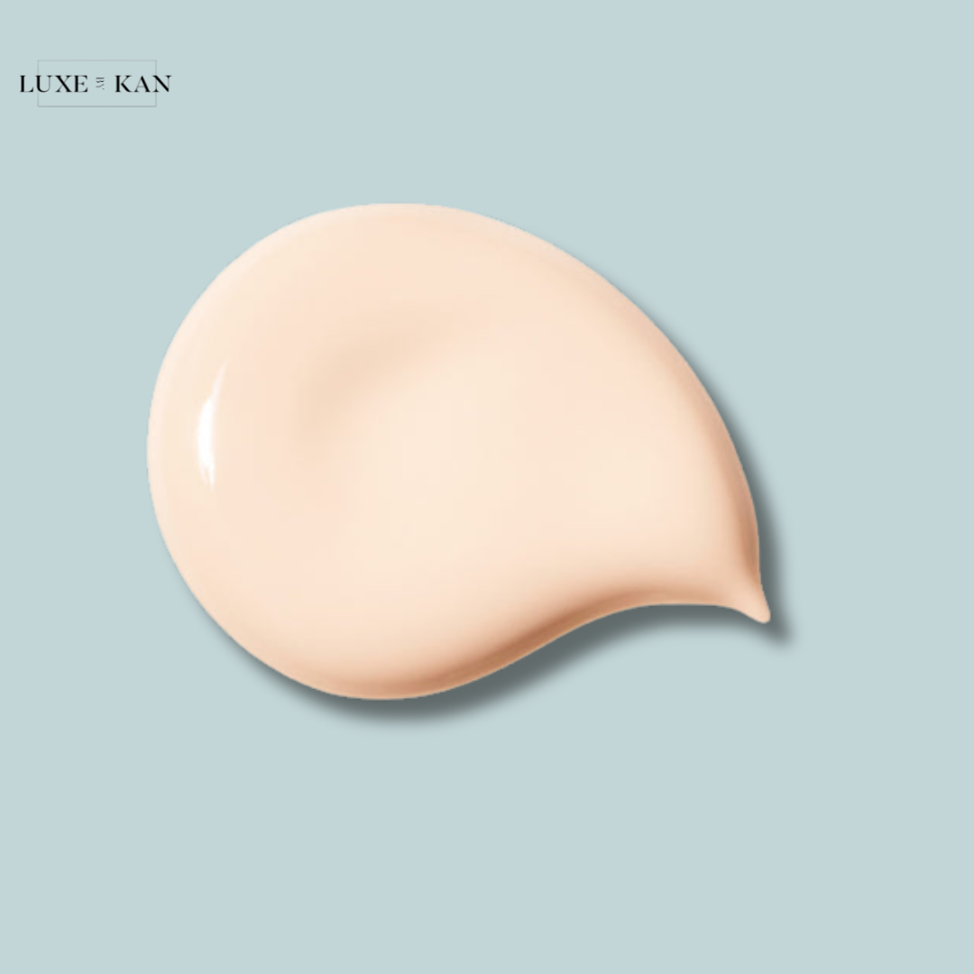 A creamy pale beige cosmetic swatch on a light blue background, showcasing a smooth texture.