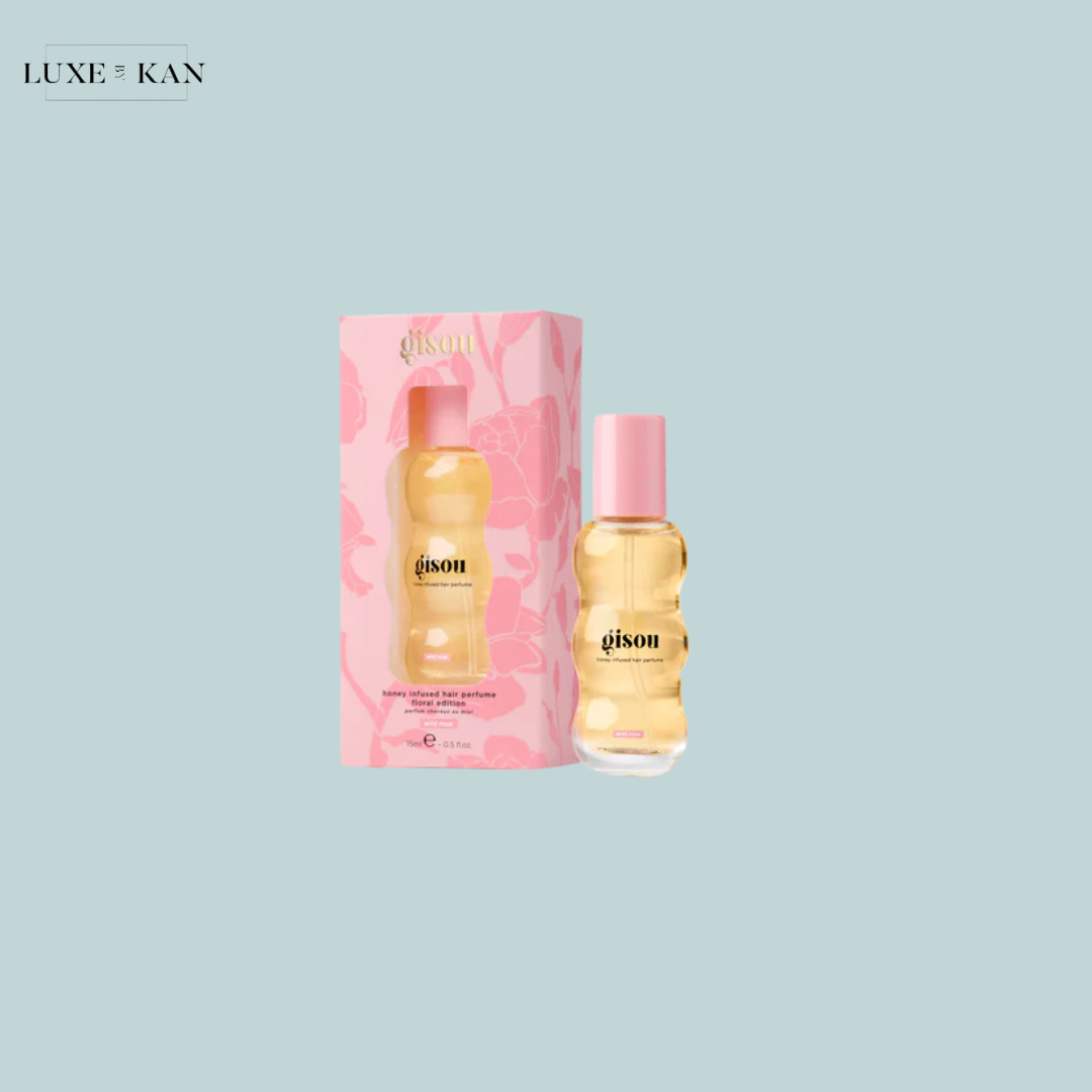 Gisou honey-infused hair perfume next to its pink floral box, set against a light blue background.