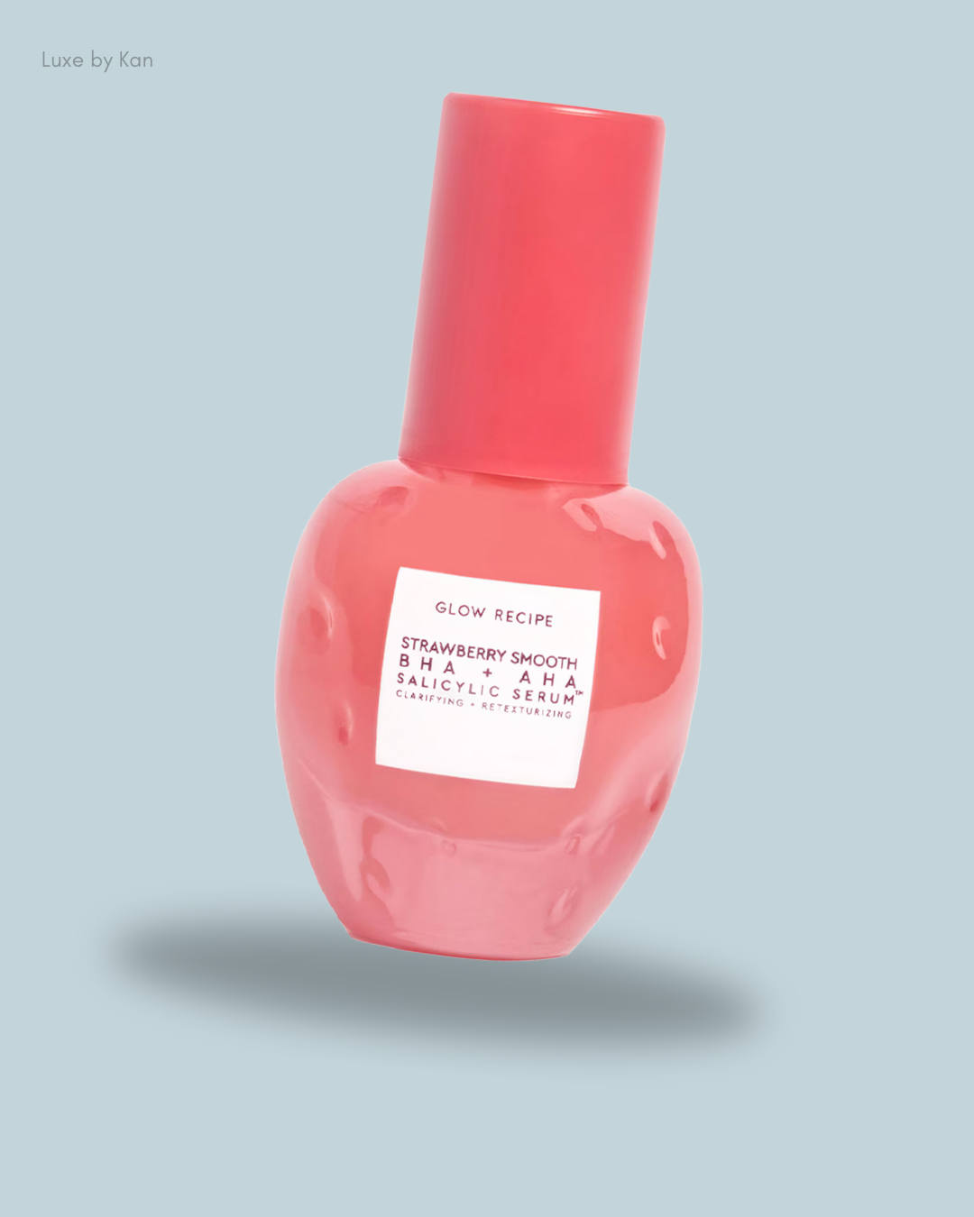A pink serum bottle labeled "Glow Recipe Strawberry Smooth BHA + AHA Salicylic Serum" against a soft blue background.