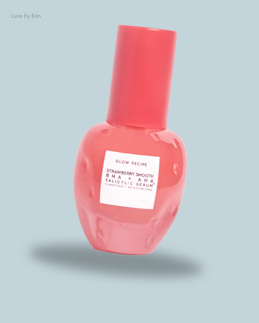 A pink serum bottle labeled "Glow Recipe Strawberry Smooth BHA + AHA Salicylic Serum" against a soft blue background.