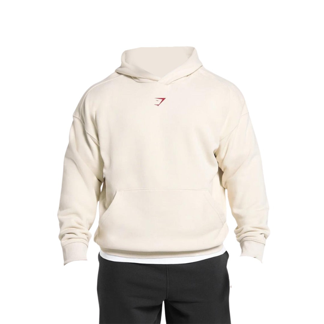 Cream-colored oversized hoodie with a small red logo on the chest, paired with dark bottoms, front view.