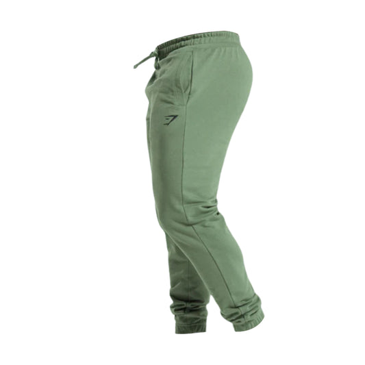 A side view of green essential oversized jogger pants featuring an adjustable waist and a small black logo on the left leg.