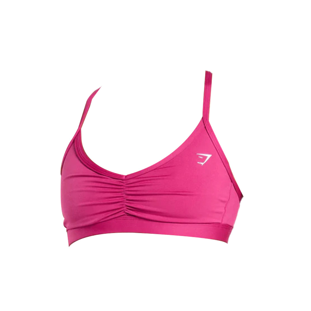 Vibrant pink sports bra with adjustable straps, featuring a front ruching detail and a small white logo on the left side.