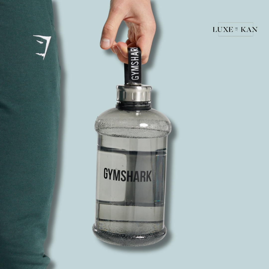 A person holds a large, transparent Gymshark water bottle with a black grip.