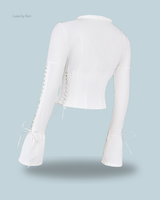 Back view of the stylish Anissa white lace-up top, showcasing side lace-up details and bell sleeves finished with delicate ribbon ties.