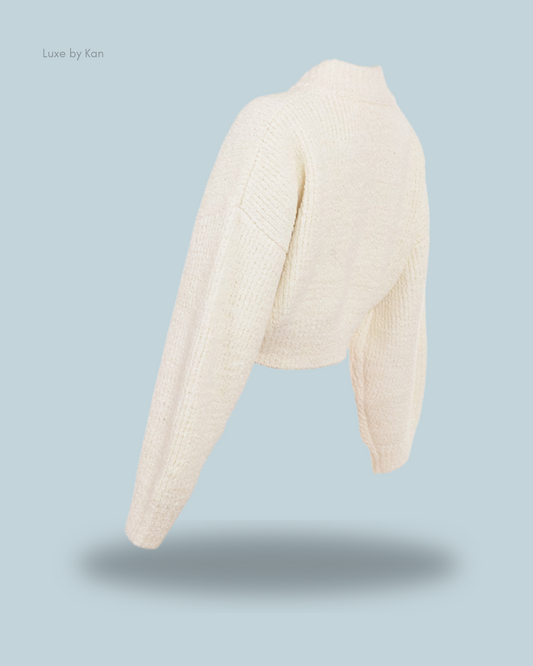 A chic, cream-colored cropped sweater with long sleeves, showcasing its textured knit design.