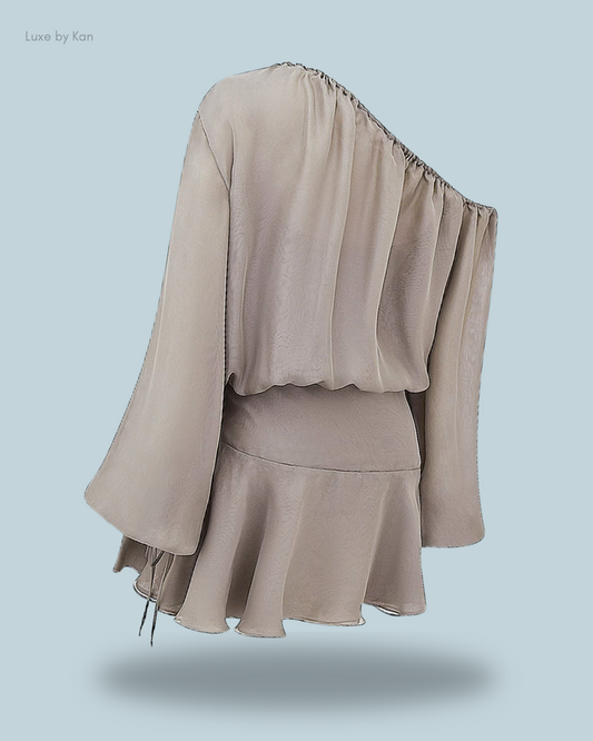 A flowing beige one-shoulder top with wide sleeves and a flared hem.