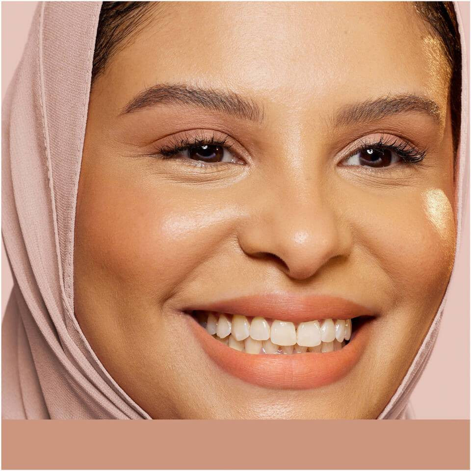 A close-up of a person wearing a soft, draped beige garment against a gently blurred background, conveying warmth and elegance.