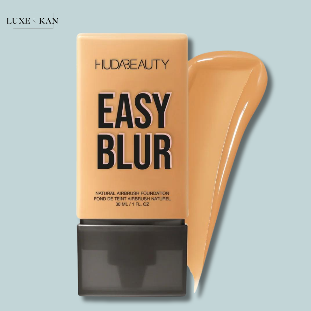 A bottle of Huda Beauty's Easy Blur foundation in a tan shade, with a flowing swatch of the foundation beside it.