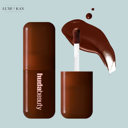 A brown Huda Beauty icy nude blush filter product with a doe-foot applicator, accompanied by a glossy chocolate swatch.