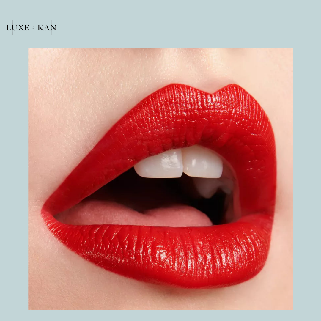 Close-up of beautifully shaped lips adorned with glossy red lipstick, showcasing white teeth and a subtle facial expression.