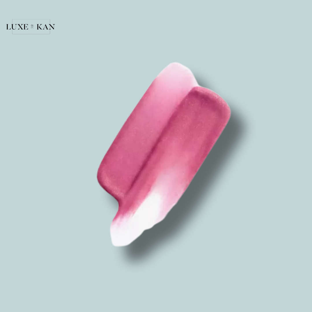A swatch of creamy lip color in a gradient of deep pink fading to soft white, set against a light blue background. Branding in corner: Luxe & Kan.