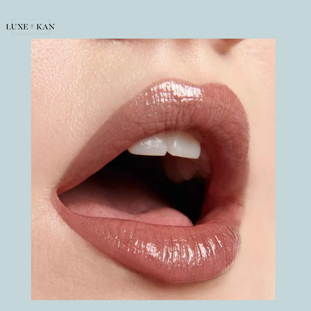 Close-up of a mouth with full, glossy nude lips slightly parted, showcasing smooth skin and a natural, elegant look.