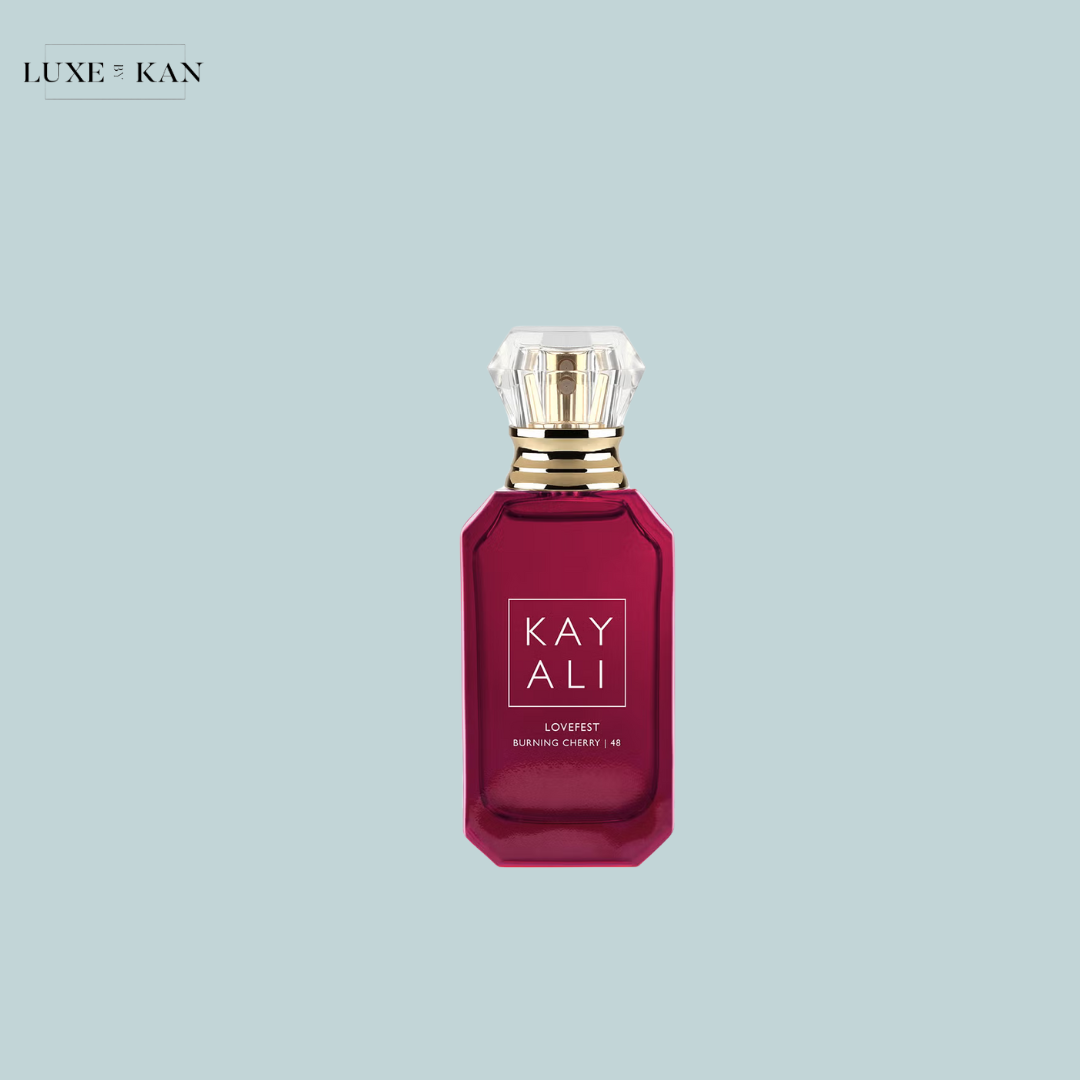 A luxurious deep red perfume bottle labeled "KAYALI Lovefest Burning Cherry | 48," topped with a diamond-shaped cap against a light blue background.