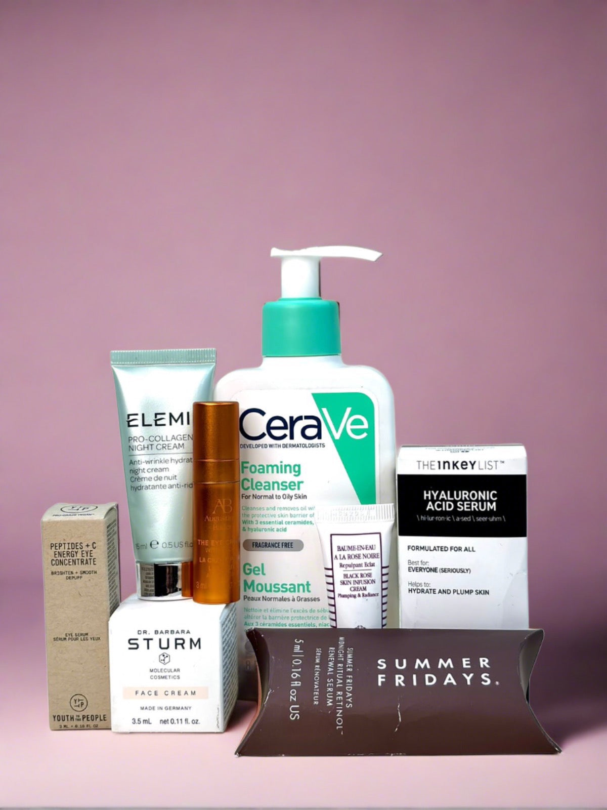 A collection of skincare products on a pink background, featuring brands like CeraVe, Elemis, The Inkey List, and Dr. Barbara Sturm.