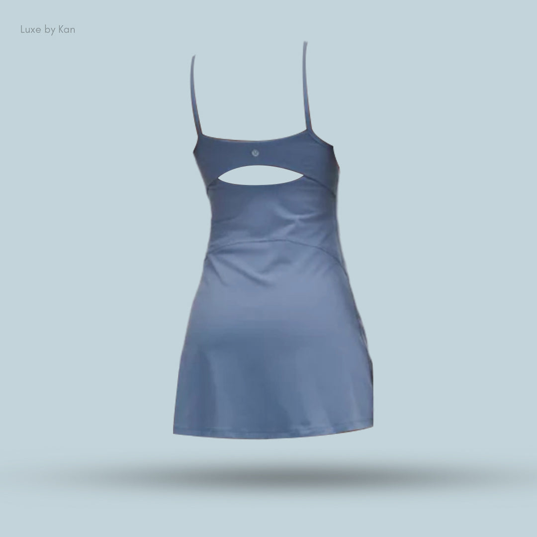 Back view of a blue athletic dress with spaghetti straps and an open cut-out design, featuring a logo at the neckline.