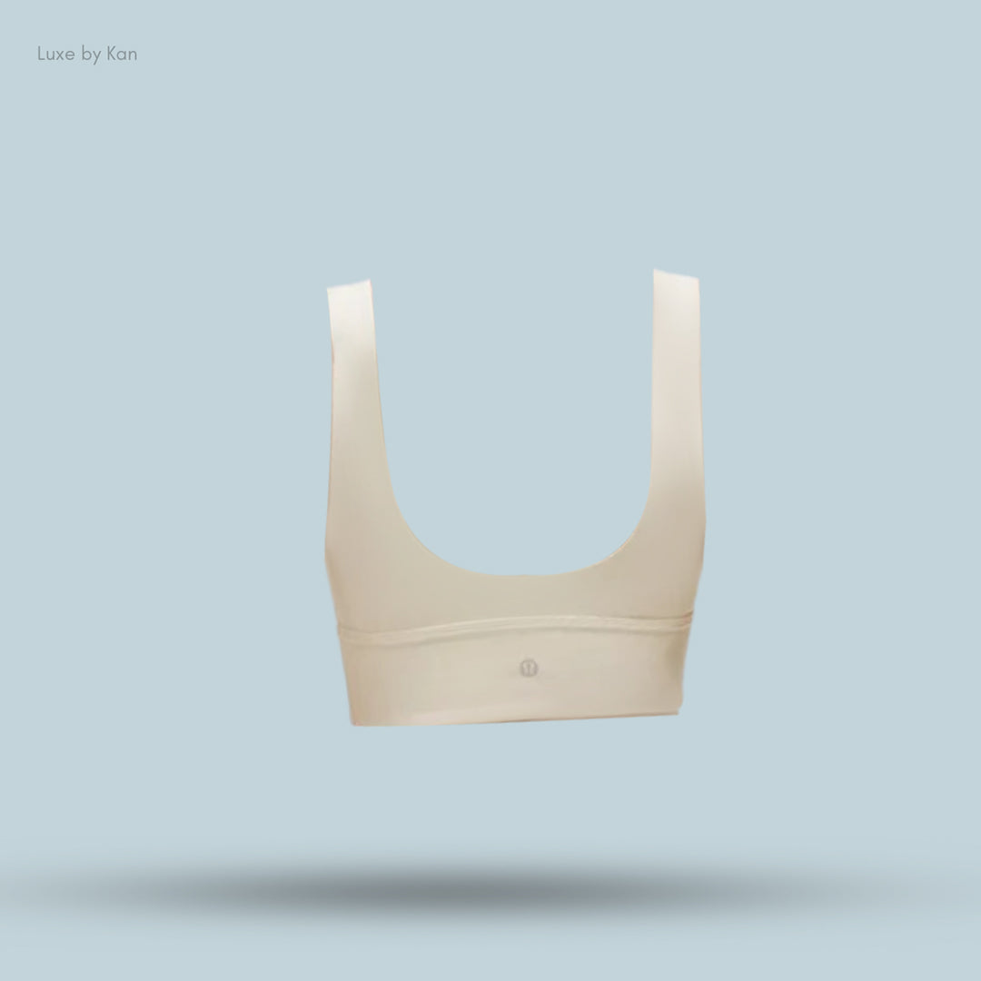 Cream-colored scoop-neck bra with wide straps, featuring a subtle logo.