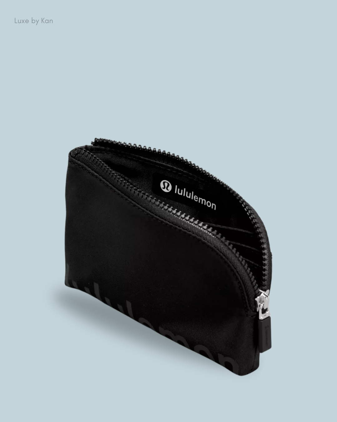 Black zippered pouch with lululemon branding, partially open, against a light blue background.