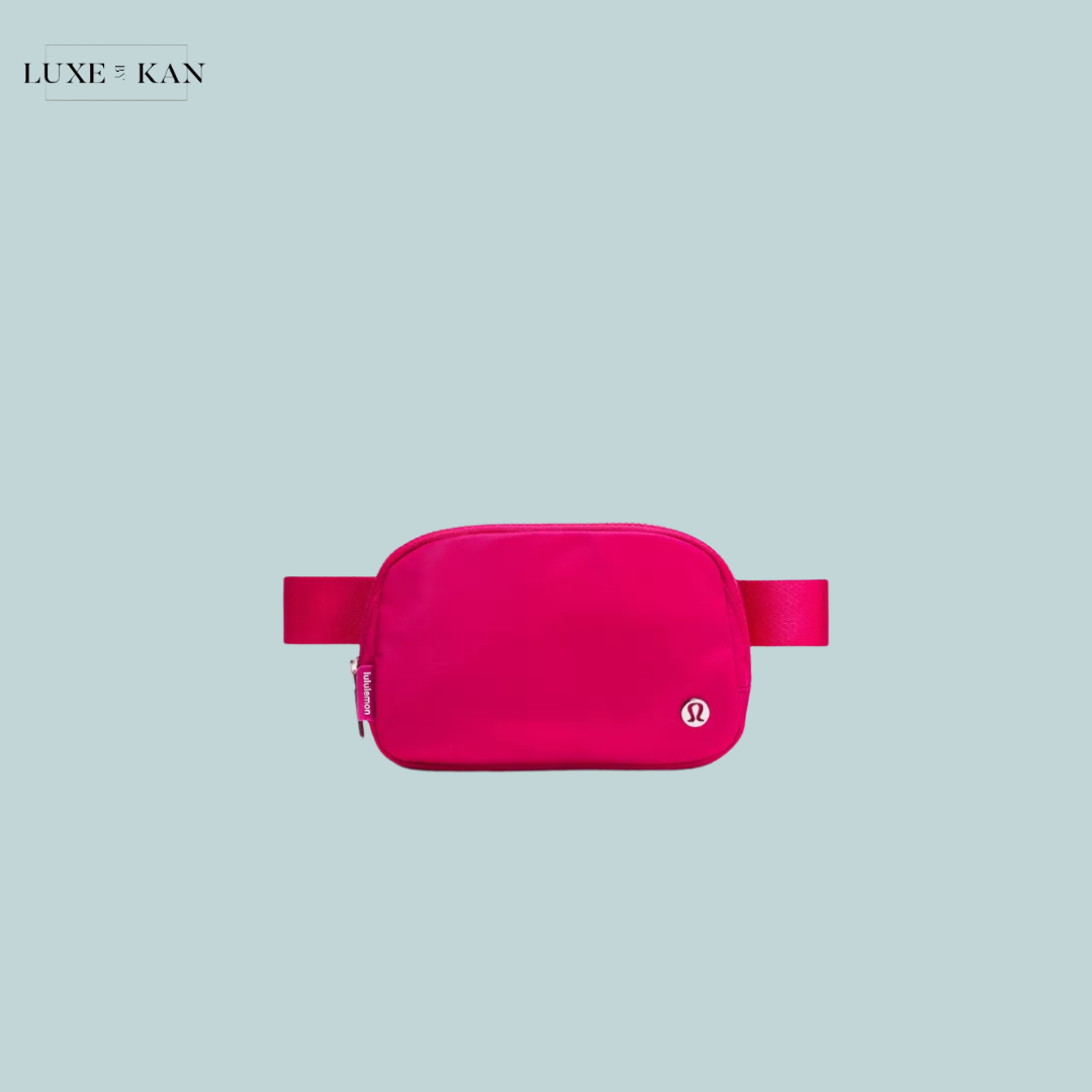 A vibrant pink travel pouch with a zipper and strap, featuring a logo.