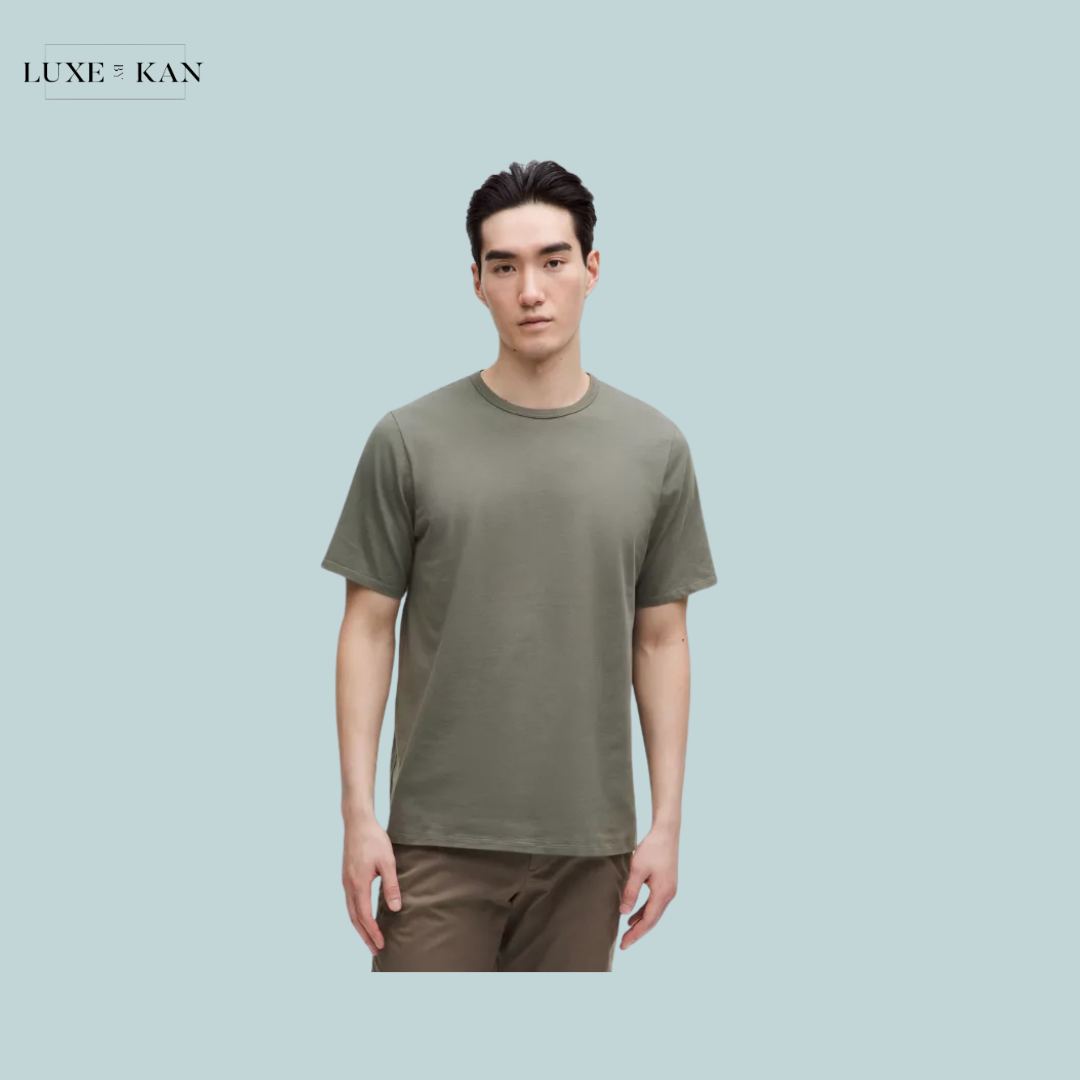 A model wears a short-sleeve olive green t-shirt paired with brown pants.