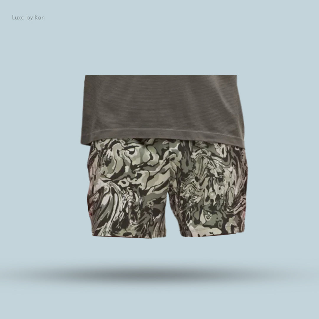 A model wearing Pace Breaker Linerless Short 5" with swirls of green and gray, paired with a dark gray shirt for a bold, athletic look.