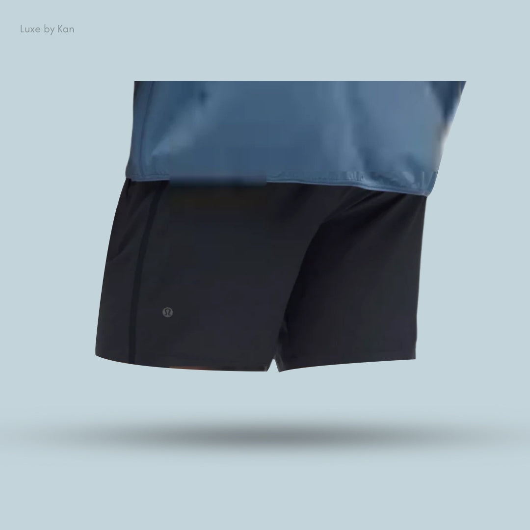 A person wearing black Pace Breaker Linerless Athletic Shorts 5" and a blue top, highlighting the shorts' sleek and sporty design.