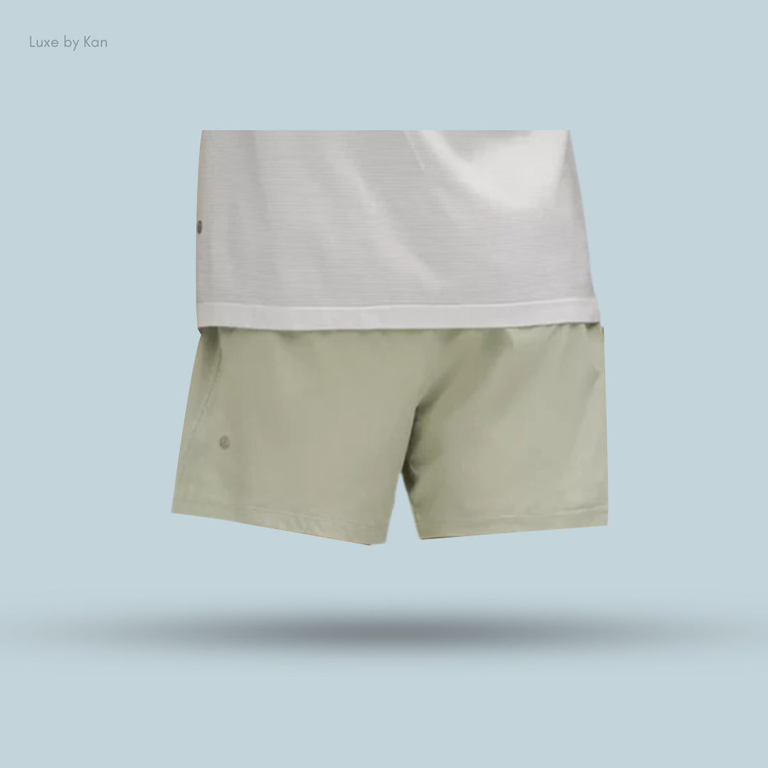 A pair of khaki shorts displayed with a white shirt, on a light blue background, showcasing a stylish and casual outfit.