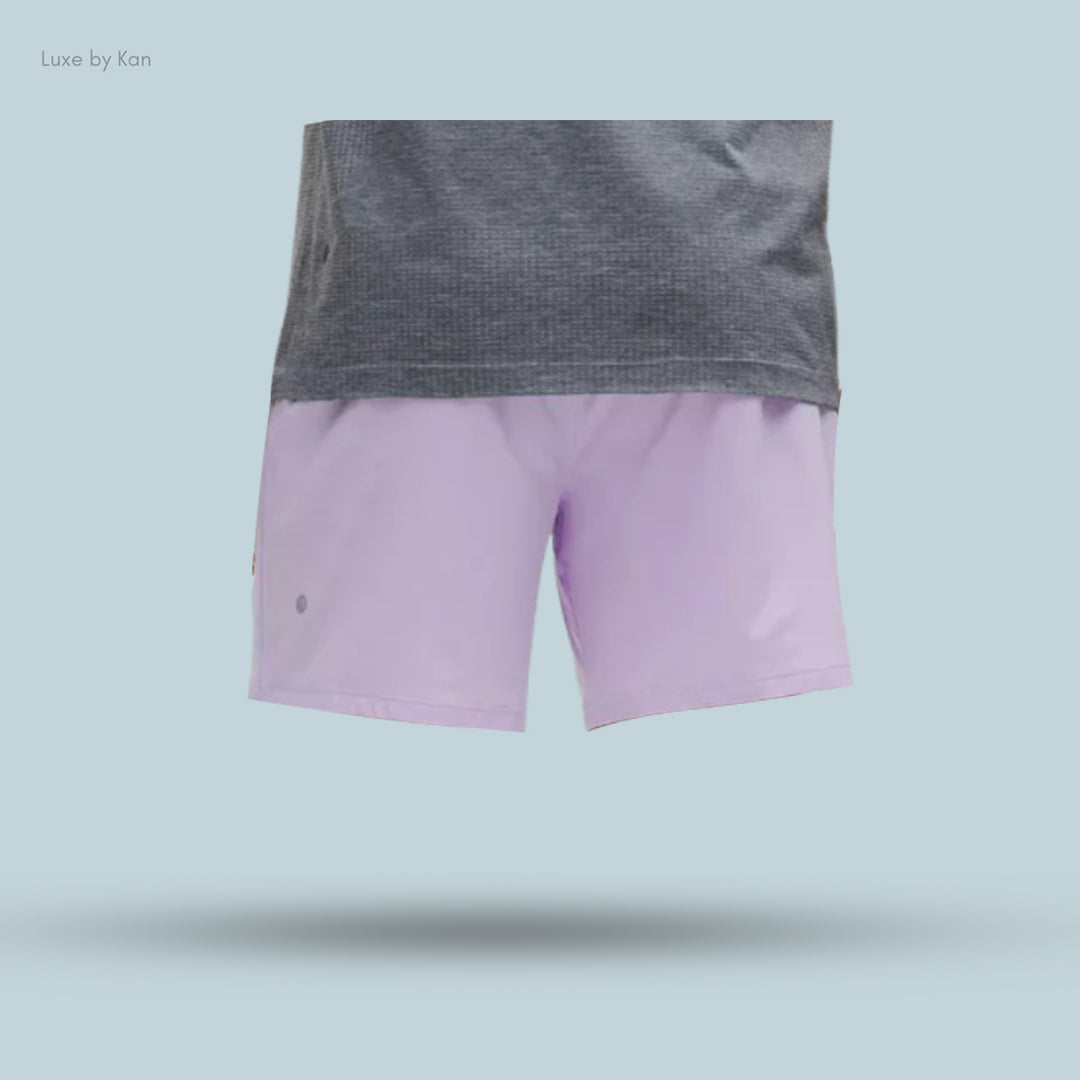 A model's waist shows a gray top and lavender shorts against a light blue background, highlighting stylish, casual wear.