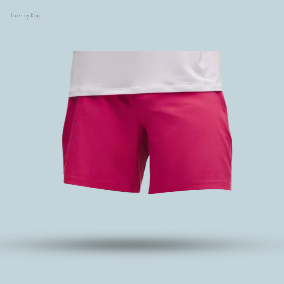 A close-up of vibrant pink athletic shorts paired with a white top.